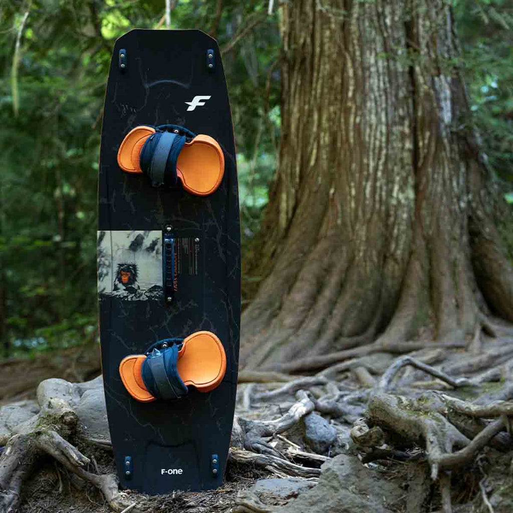 F-ONE Set Trax Carbon Kite board steht im Wald neben einem Baum